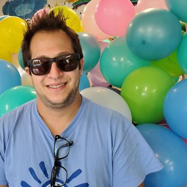 Mitchell Landsberg, posing near a lot of colorful balloons