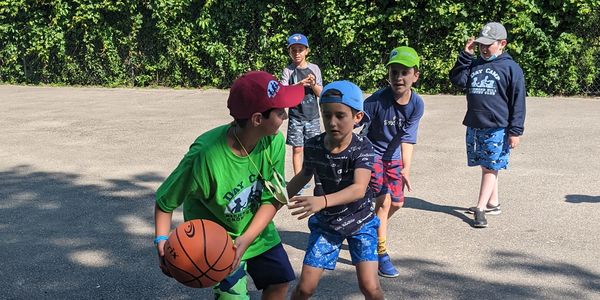 group of boys playing basketball outside in the summer