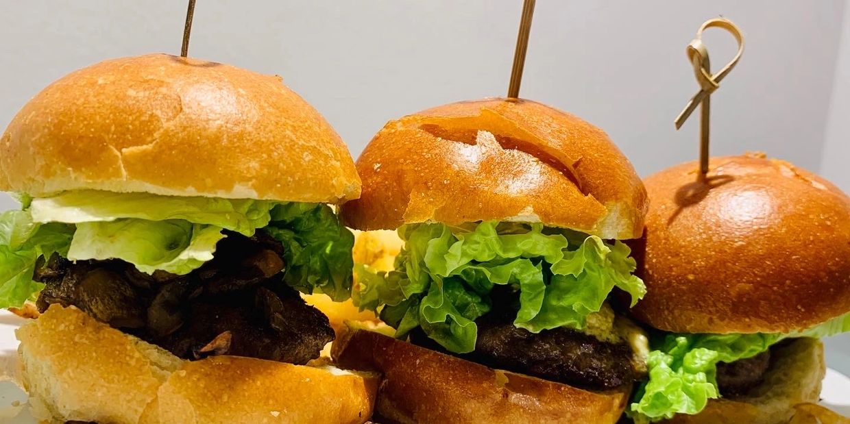 three hamburgers with lettuce and mushrooms on a plate