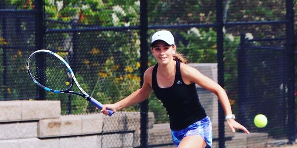 a young girl playing tennis in shorts and tank top