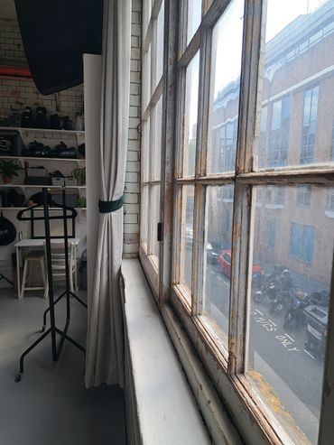 Sunlight streams through a vintage window into a cozy, organized studio space.