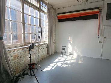 Bright photography studio with white backdrop and lighting equipment.
