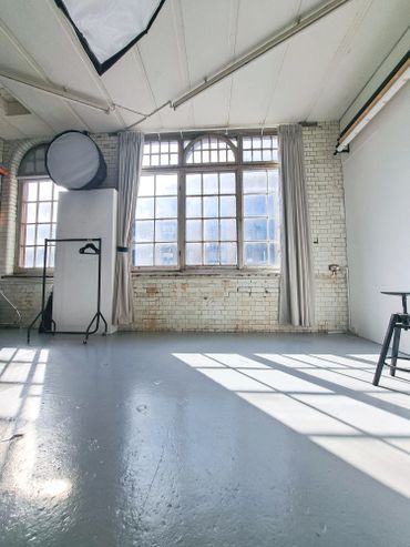 Bright photography studio with large windows and soft lighting equipment.