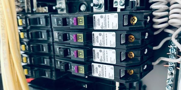 Close-up of electrical circuit breakers and wiring inside a panel.