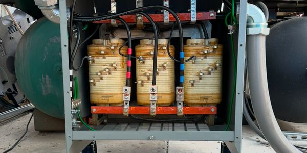 Open electrical transformer box showing coils and wiring inside.