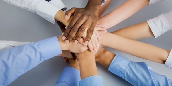Diverse hands stacked together symbolizing unity and teamwork.