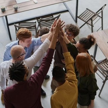 Group of diverse colleagues joining hands in a team cheer.