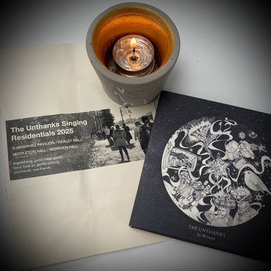 A lit tealight, The Unthanks singing residential brochure and The Unthanks In Winter cd.