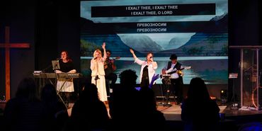 Worship band leads a congregation in song with bilingual lyrics on screen.