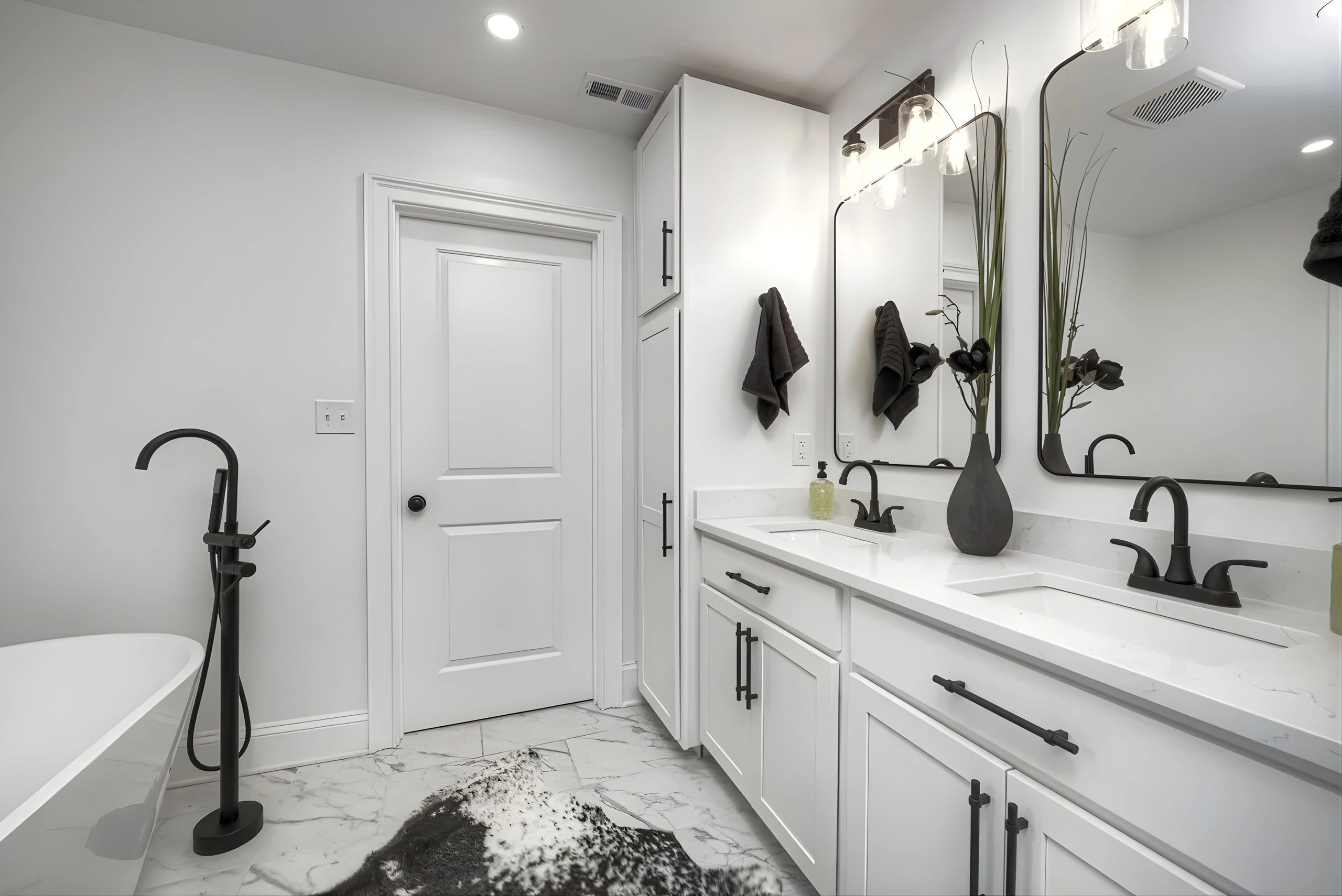 Modern white bathroom with black fixtures and a decorative vase.