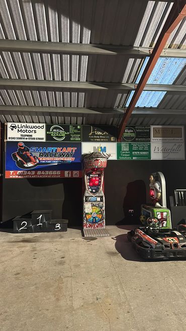 Indoor go-kart racing area with podium and arcade boxing game.