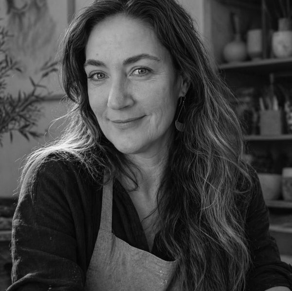 Black and white portrait of a smiling woman with long hair and an apron.