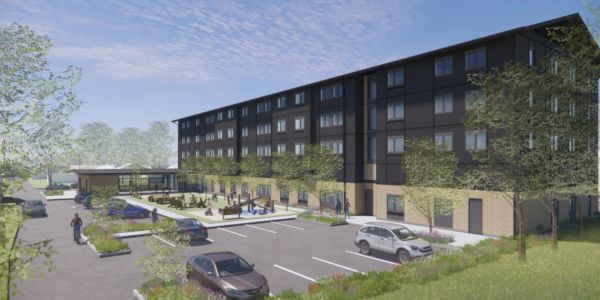 Modern apartment building with parking and green spaces.