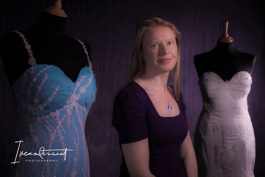 Susie sitting in-between two wedding dresses she has made. Photo by Incandescent Photography