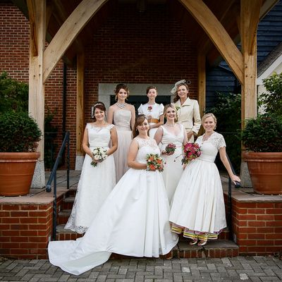 Group of 7 models in various wedding dresses made by Susie Grist Couture on steps outside venue 