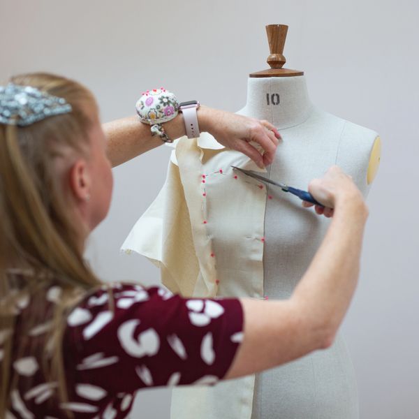 Susie pinning and cutting a wedding dress pattern in calico on a tailors dummy