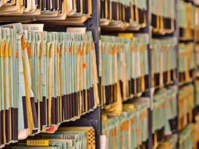 Rows of organized file folders on shelves in an office or archive.