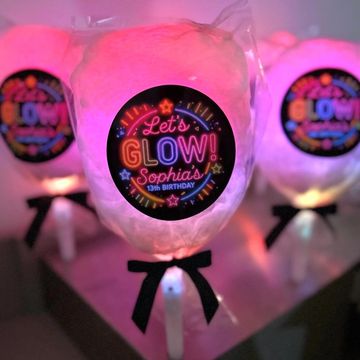 Glowing cotton candy sticks with personalized birthday labels and black bows.