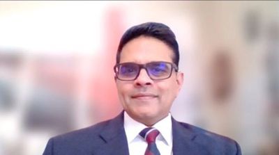 Man in glasses wearing a suit and tie, smiling at the camera.