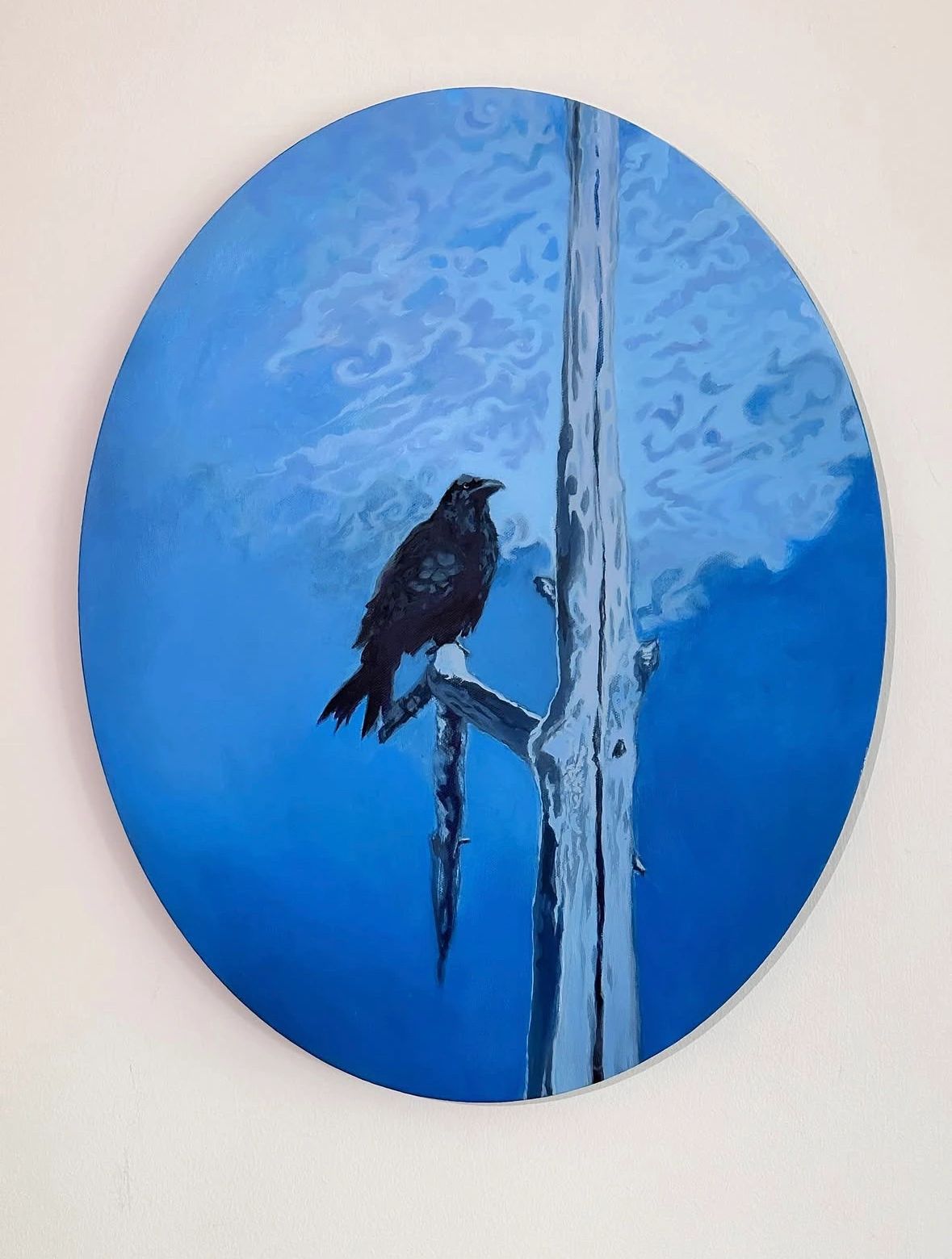 Sophia Polizzi painting of a dark bird perched beside a pale tree against a luminous blue background