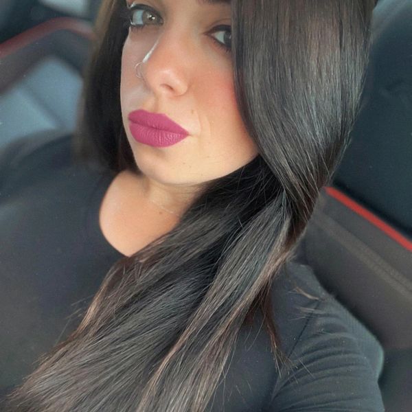 Woman with long dark hair and bold lipstick taking a selfie.