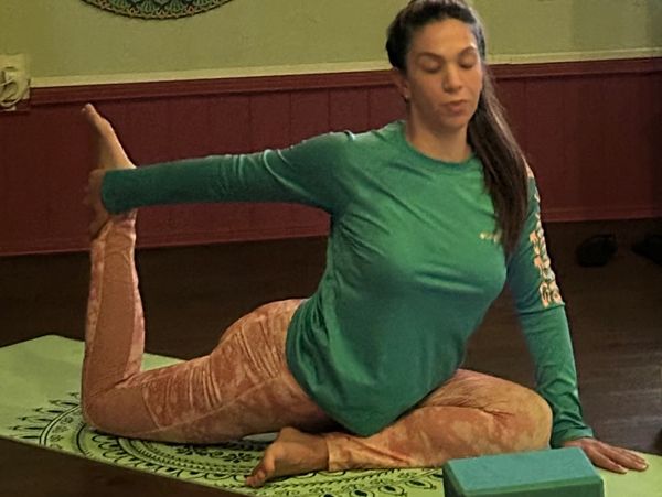 Woman practicing yoga in a seated pose on a mat indoors.