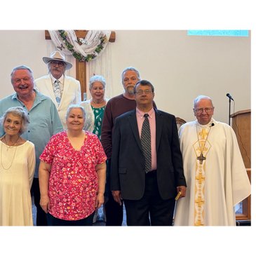 A group of eight people posing inside a church, including a priest.