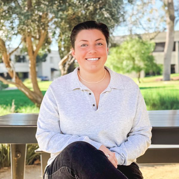 Young woman sitting on a bench outdoors, smiling.