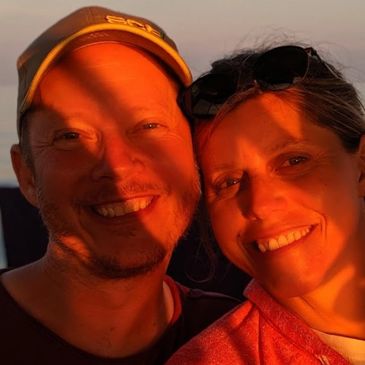 Couple smiling warmly in sunset light.