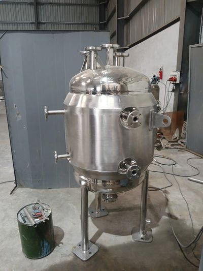 Stainless steel industrial vessel inside a workshop.
