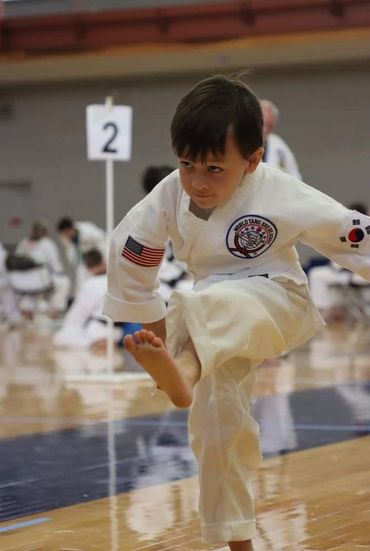 Young karate / martial arts / Tang Soo Do student performing kick at event