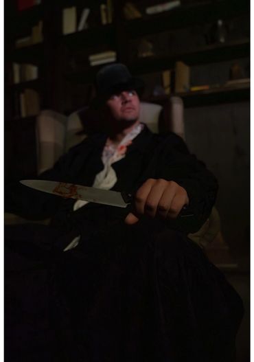 A person holding a blood-stained knife in a dark room.