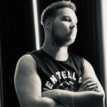 Black and white portrait of a man with arms crossed, looking contemplative.