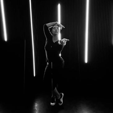 Black and white photo of a dancer posing with illuminated vertical lights.