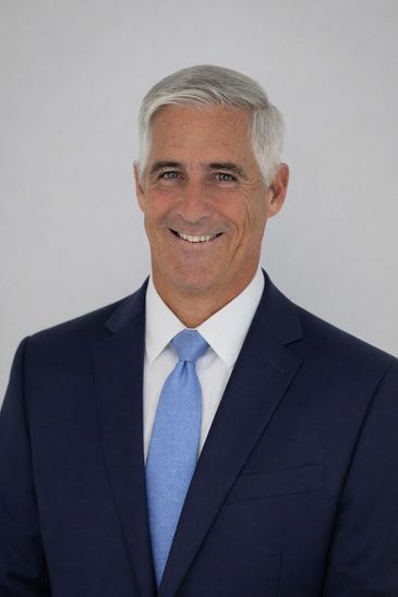 Smiling man in a suit and light blue tie.