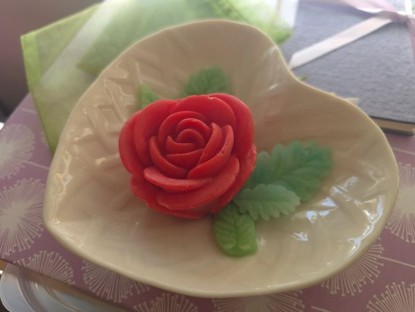 Red rose and green leaves on heart shape bowl