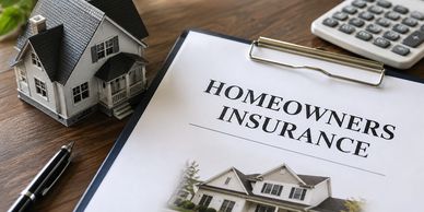 Homeowners insurance document with a house model, pen, and calculator on a wooden table.