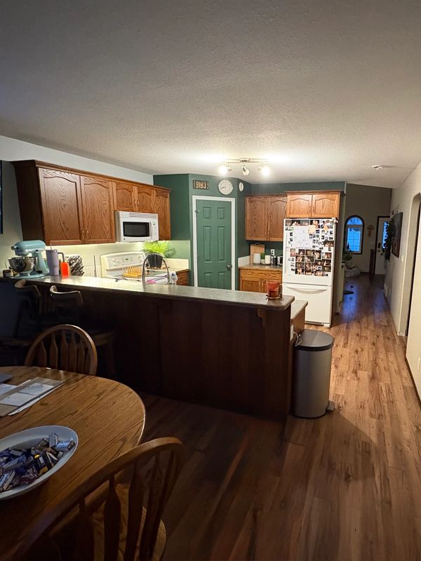 Cozy kitchen with wooden cabinets, green door, and dining table.