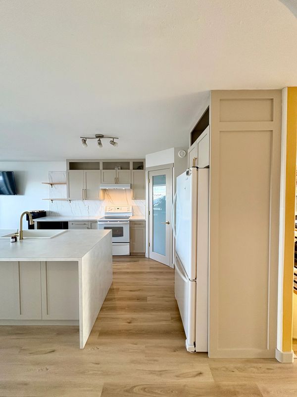 Modern kitchen with light wood floors and white cabinetry.