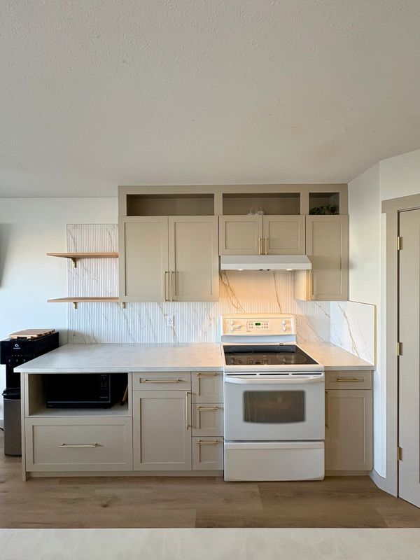 Modern kitchen with beige cabinets, white stove, and marble backsplash.