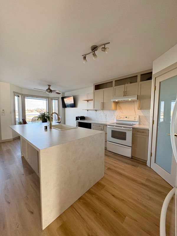 Bright modern kitchen with a large island and wooden floor.