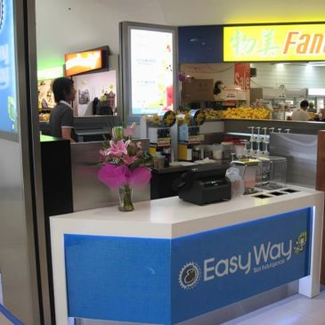 Counter area of Easy Way tea franchise with flowers and equipment.