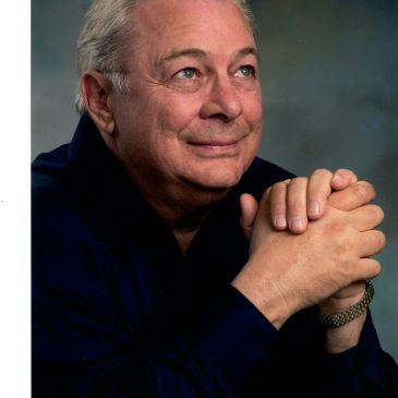 Elderly man with clasped hands, looking thoughtfully upward.