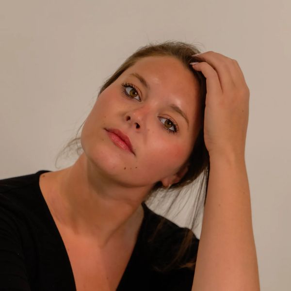Portrait of a woman with hand on head and soft expression.
