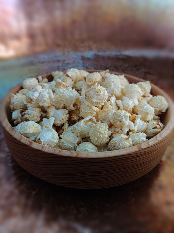 Wooden bowl filled with freshly popped popcorn.