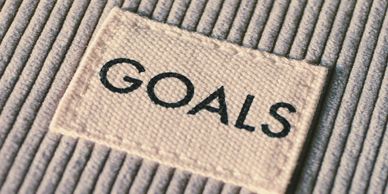 A fabric patch with the word 'GOALS' sewn onto textured clothing.