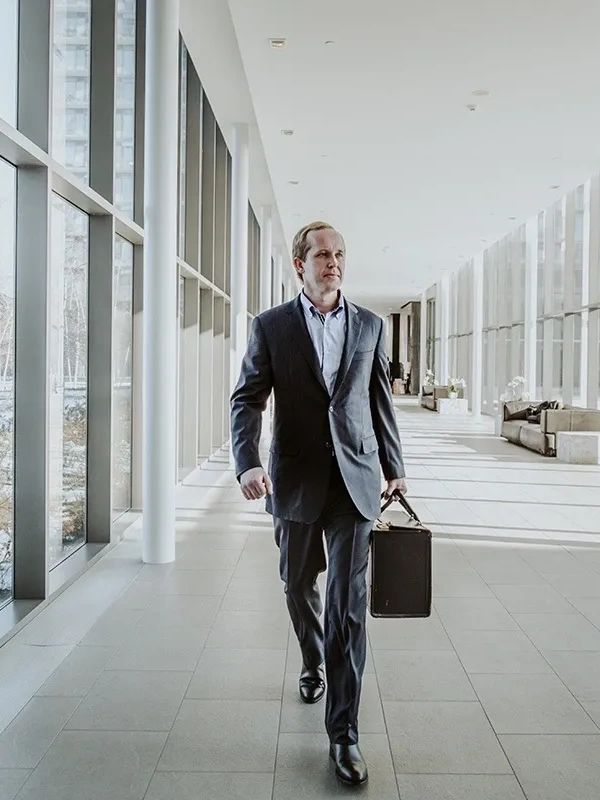 Businessman walking in a modern office corridor with a briefcase.