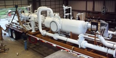 Two white ASME Pressure Vessel skids loaded on two trailers