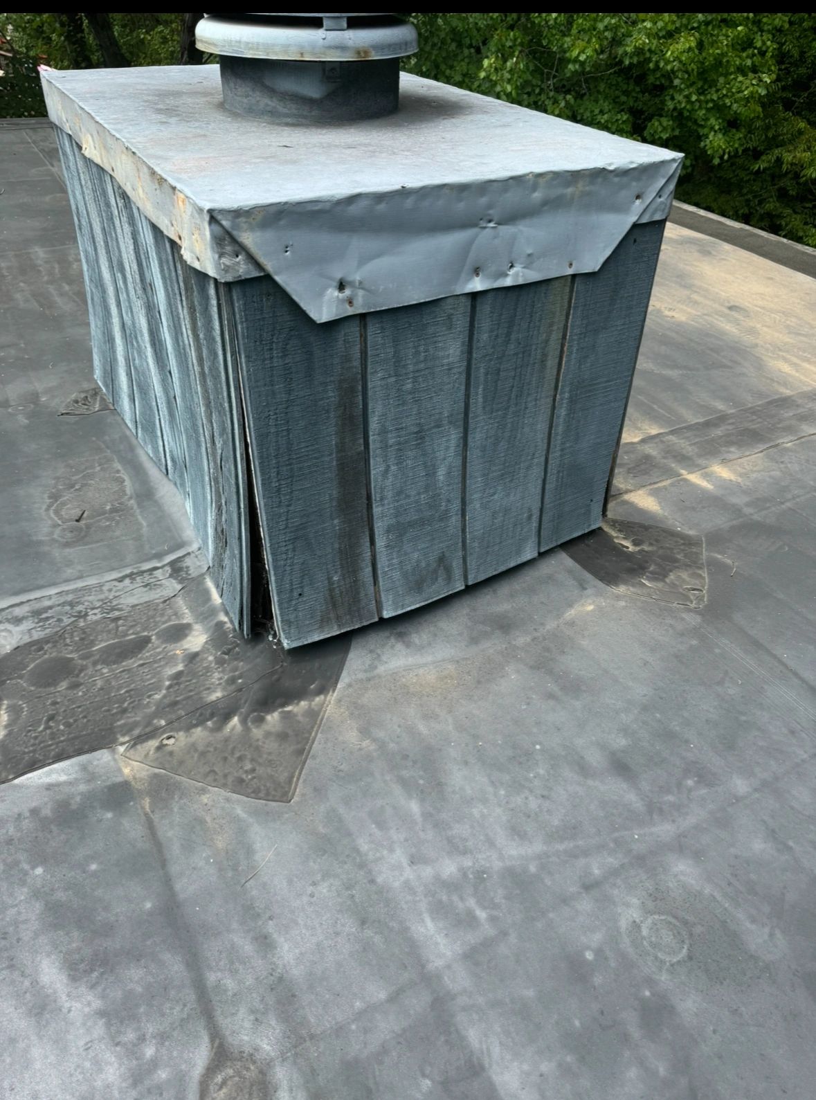 Weathered metal chimney on a flat roof.