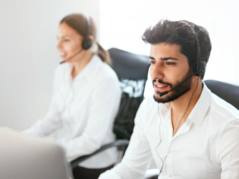 Two call center agents in headsets assisting customers.